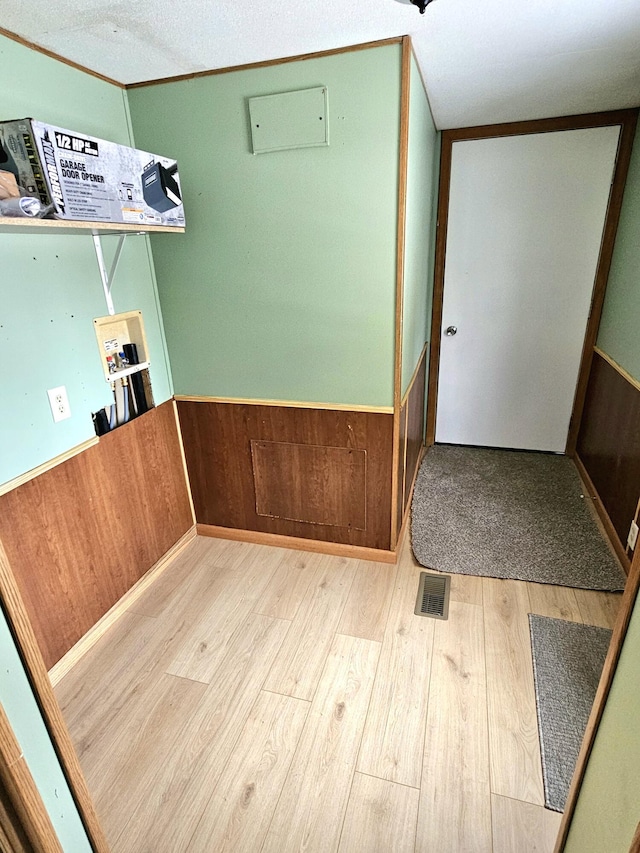 interior space with washer hookup, wooden walls, and light hardwood / wood-style flooring