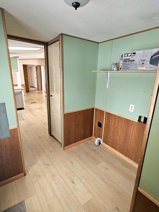 clothes washing area featuring light hardwood / wood-style flooring and wood walls