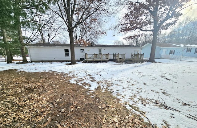 snow covered rear of property with a deck