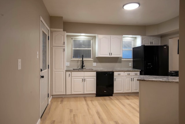 kitchen featuring sink, light stone counters, black appliances, light wood-type flooring, and white cabinets