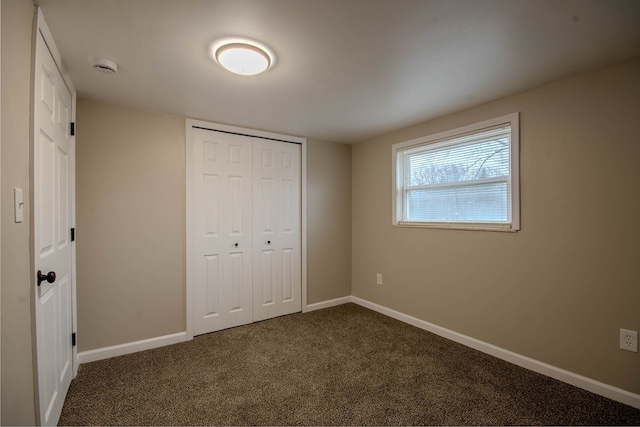 unfurnished bedroom featuring dark carpet and a closet