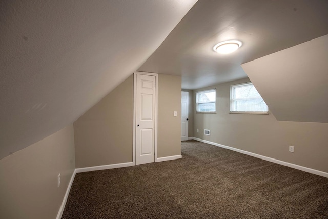 bonus room featuring dark colored carpet and lofted ceiling