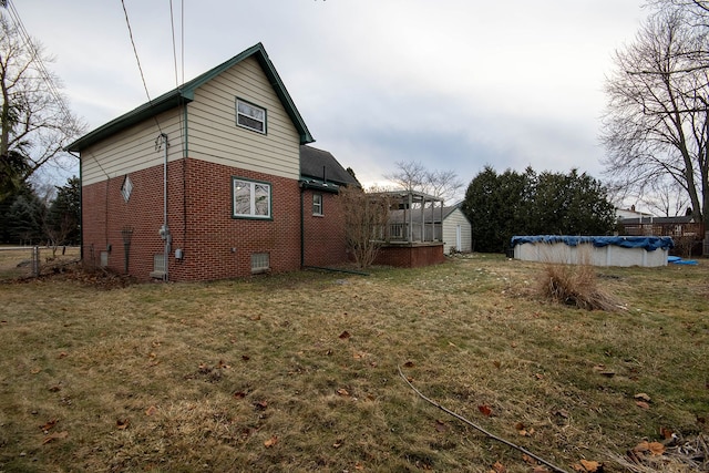 view of side of home featuring a storage shed, a yard, and a covered pool