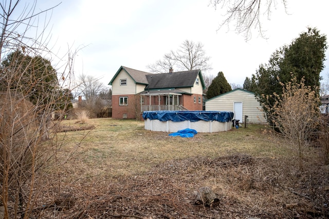 back of house with a lawn and a covered pool