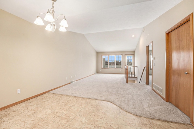 carpeted empty room with vaulted ceiling and a notable chandelier