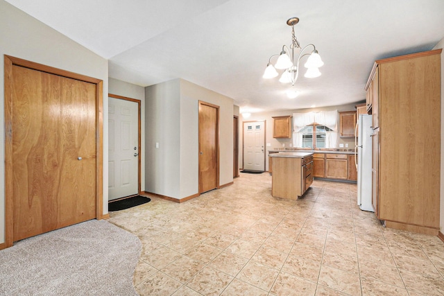 kitchen with white fridge, a center island, a chandelier, and decorative light fixtures