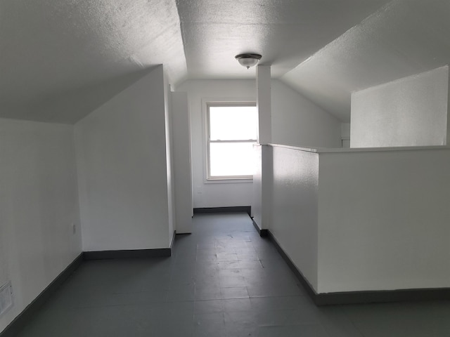 additional living space with lofted ceiling and a textured ceiling