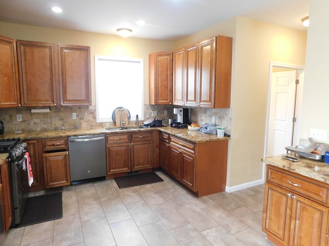 kitchen with sink, light stone counters, tasteful backsplash, light tile patterned floors, and appliances with stainless steel finishes