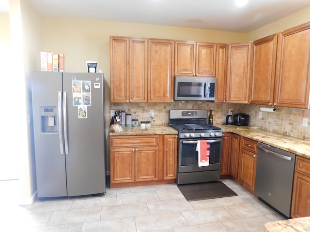 kitchen featuring tasteful backsplash, stainless steel appliances, and light tile patterned flooring