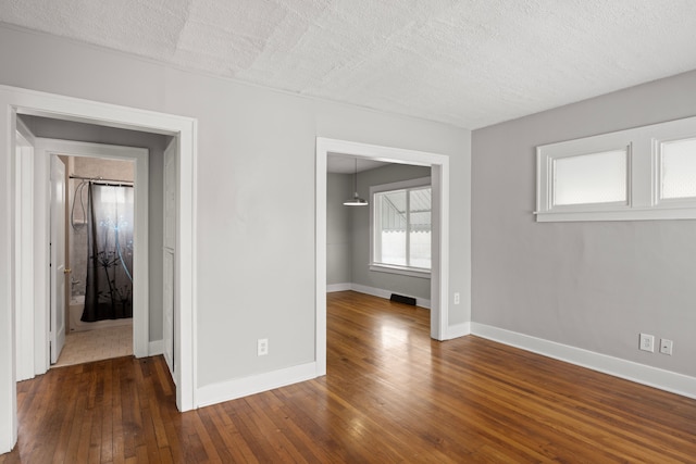 unfurnished room with dark wood-type flooring and a textured ceiling