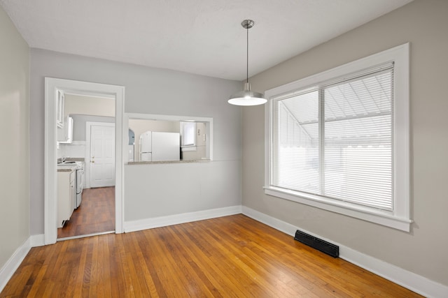 unfurnished dining area featuring plenty of natural light and hardwood / wood-style floors