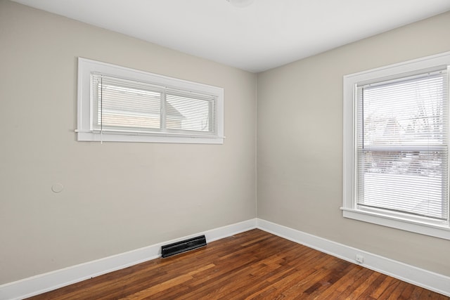 empty room with dark hardwood / wood-style flooring and a wealth of natural light