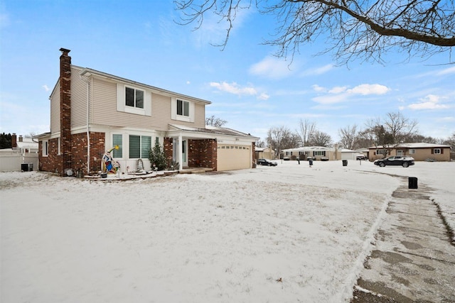 snow covered house with a garage and central AC unit