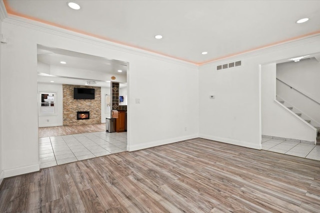 spare room featuring crown molding, a fireplace, and light hardwood / wood-style floors