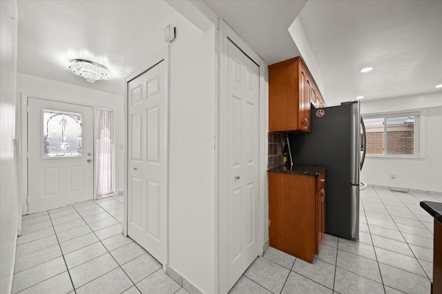 kitchen with stainless steel fridge, decorative backsplash, and light tile patterned floors