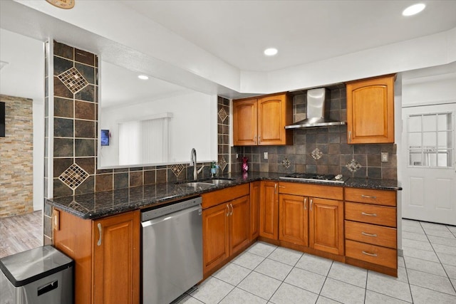 kitchen with appliances with stainless steel finishes, tasteful backsplash, sink, dark stone countertops, and wall chimney exhaust hood