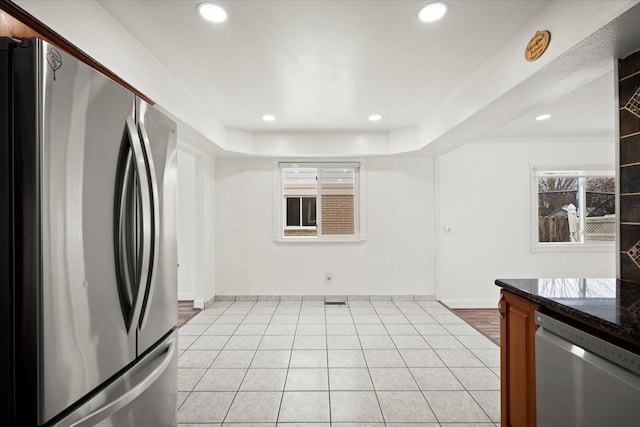 kitchen with light tile patterned flooring, dark stone counters, and appliances with stainless steel finishes