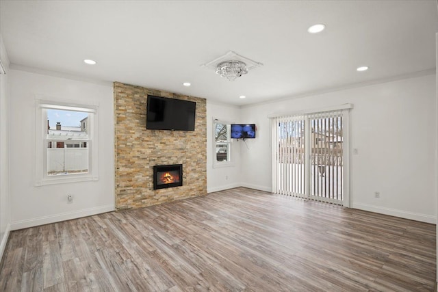 unfurnished living room featuring hardwood / wood-style flooring, ornamental molding, and a stone fireplace