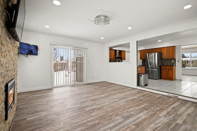 unfurnished living room featuring a stone fireplace, a healthy amount of sunlight, and light hardwood / wood-style flooring