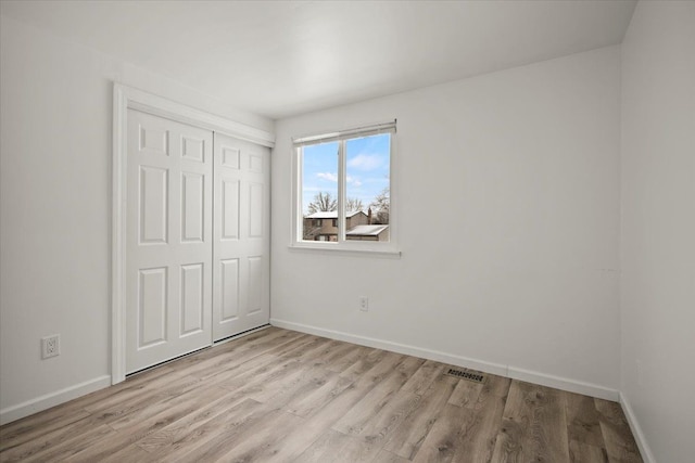 unfurnished bedroom with light wood-type flooring and a closet