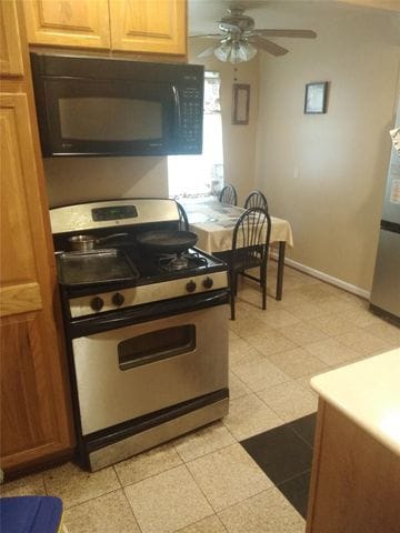 kitchen featuring light tile patterned floors, gas range, and ceiling fan