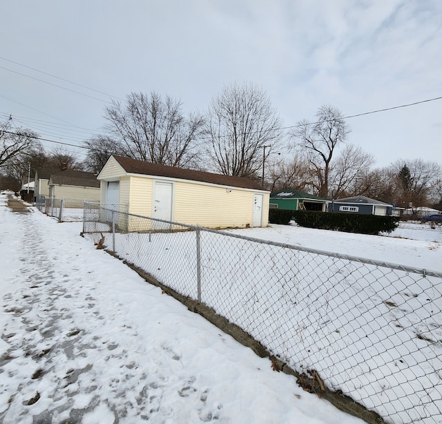 view of snowy exterior with a garage and an outbuilding