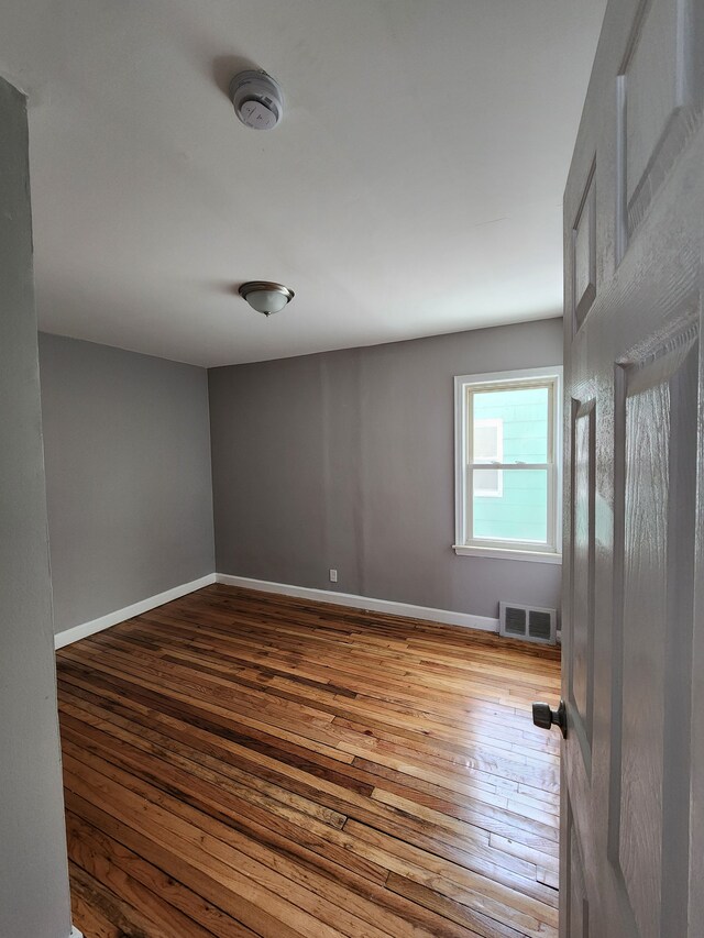 empty room featuring hardwood / wood-style flooring, baseboards, and a smoke detector