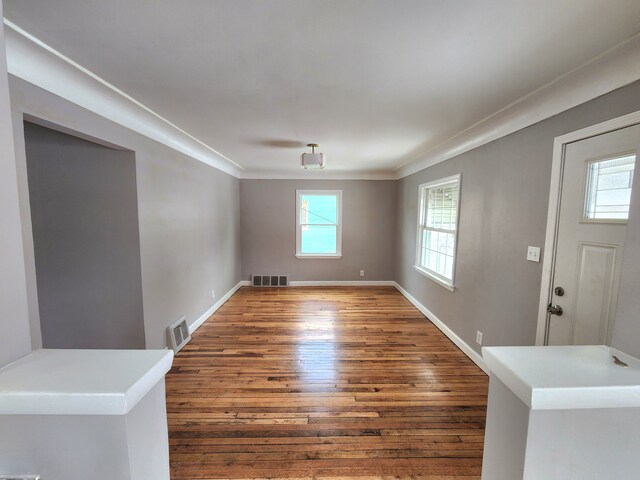 unfurnished room featuring wood finished floors, baseboards, and crown molding