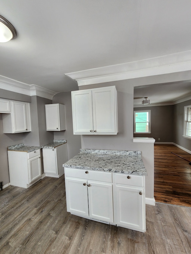 kitchen with white cabinetry, crown molding, light stone countertops, and dark wood-type flooring