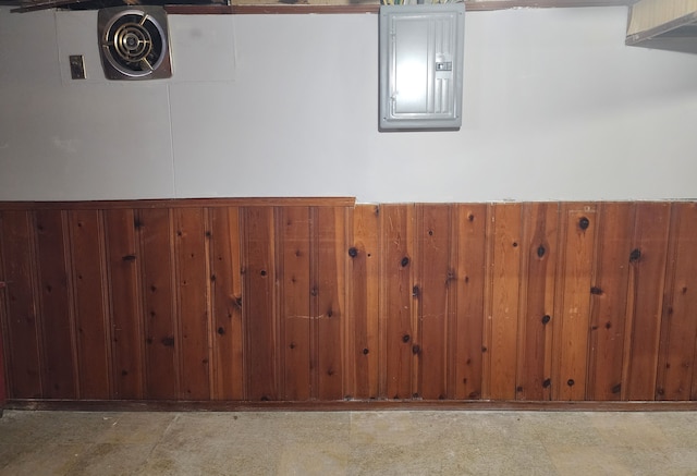 basement featuring electric panel and wooden walls