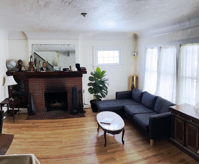 living room featuring a textured ceiling, a fireplace, and light wood-type flooring