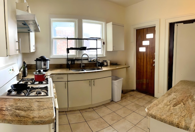 kitchen featuring sink, light tile patterned floors, white cabinets, and white gas stove