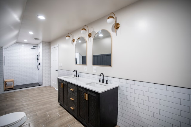 bathroom with tiled shower, lofted ceiling, tile walls, vanity, and hardwood / wood-style floors