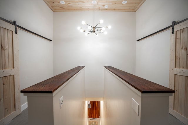 interior space with a barn door, an inviting chandelier, and wood ceiling