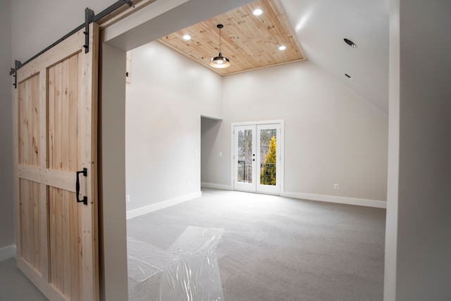 unfurnished room with high vaulted ceiling, carpet flooring, a barn door, wooden ceiling, and french doors