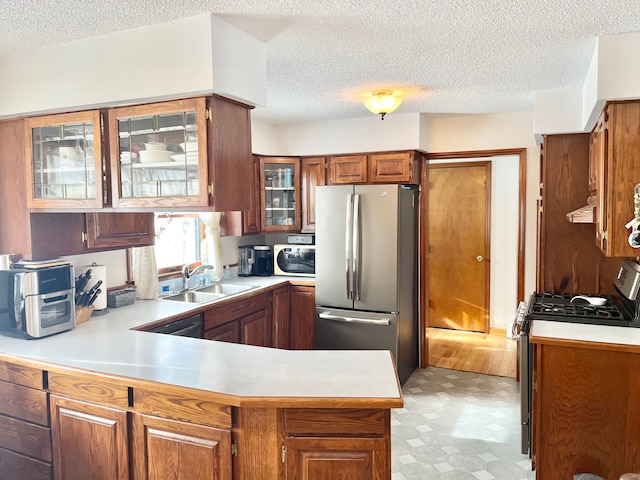 kitchen featuring stainless steel appliances, kitchen peninsula, sink, and a textured ceiling