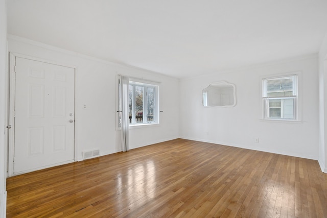 spare room with crown molding, wood-type flooring, and plenty of natural light