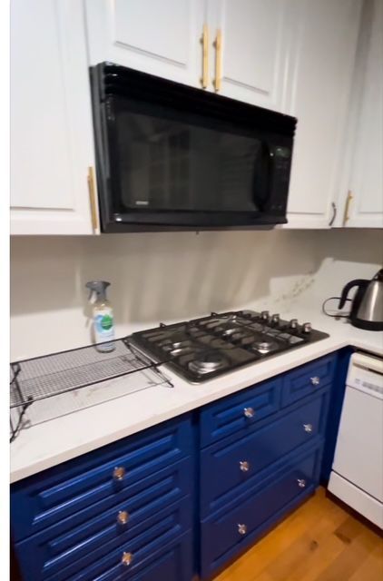 kitchen featuring hardwood / wood-style floors, black appliances, white cabinets, and blue cabinets