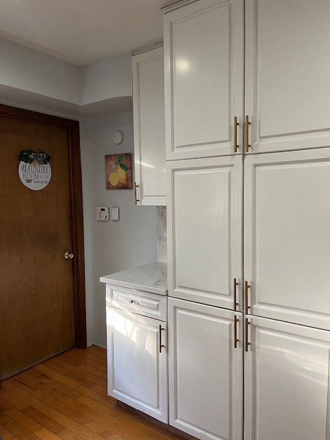 kitchen featuring white cabinetry, light stone counters, and light hardwood / wood-style flooring