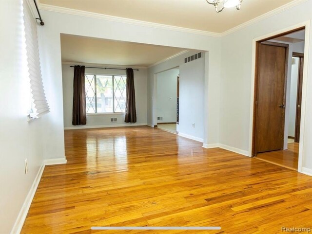 empty room with crown molding and light hardwood / wood-style floors