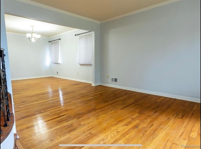 unfurnished room with hardwood / wood-style flooring, crown molding, and an inviting chandelier