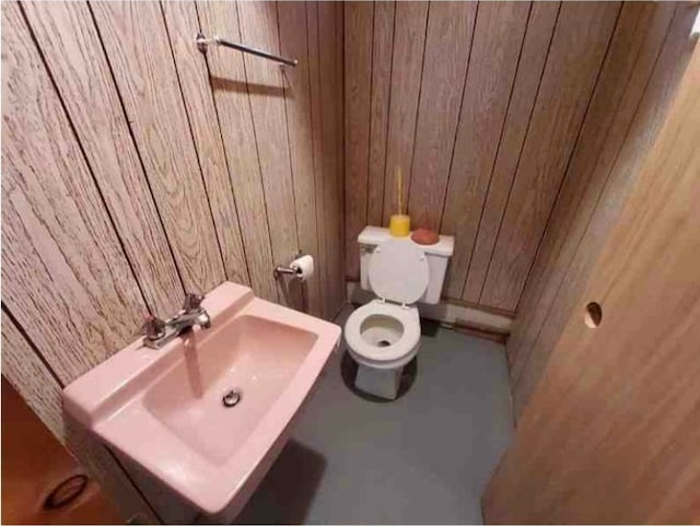 bathroom featuring sink, toilet, and wood walls