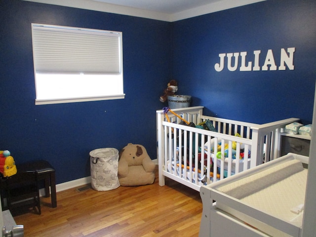 bedroom with a crib and hardwood / wood-style floors