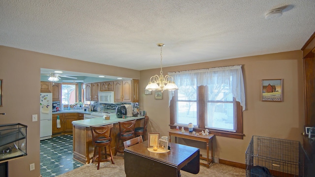 kitchen with white appliances, tasteful backsplash, ceiling fan with notable chandelier, decorative light fixtures, and kitchen peninsula