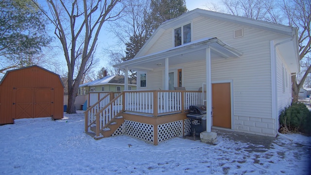 snow covered rear of property with a storage unit