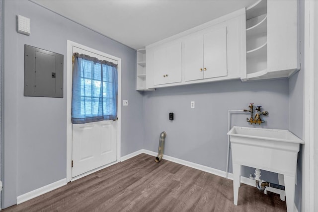 laundry room featuring sink, hardwood / wood-style flooring, cabinets, electric panel, and hookup for an electric dryer