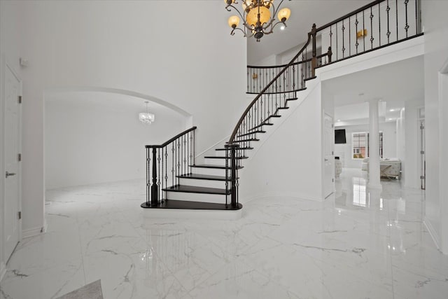 stairway with a notable chandelier and a towering ceiling