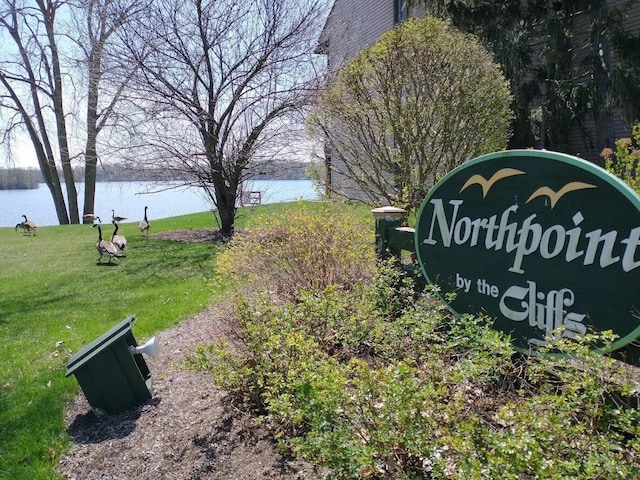 community sign with a lawn and a water view