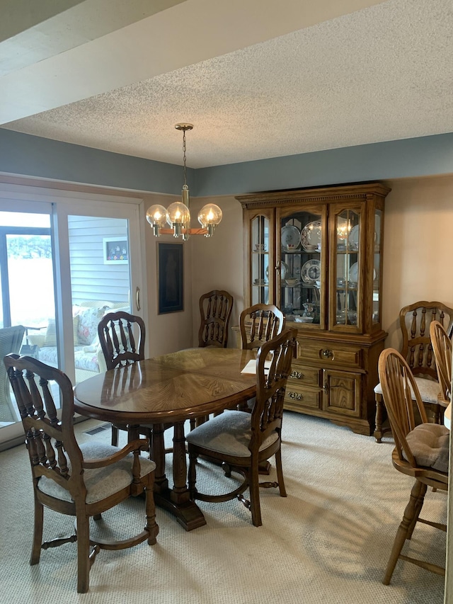 carpeted dining room featuring a notable chandelier and a textured ceiling