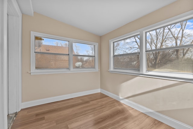 spare room featuring hardwood / wood-style flooring and vaulted ceiling